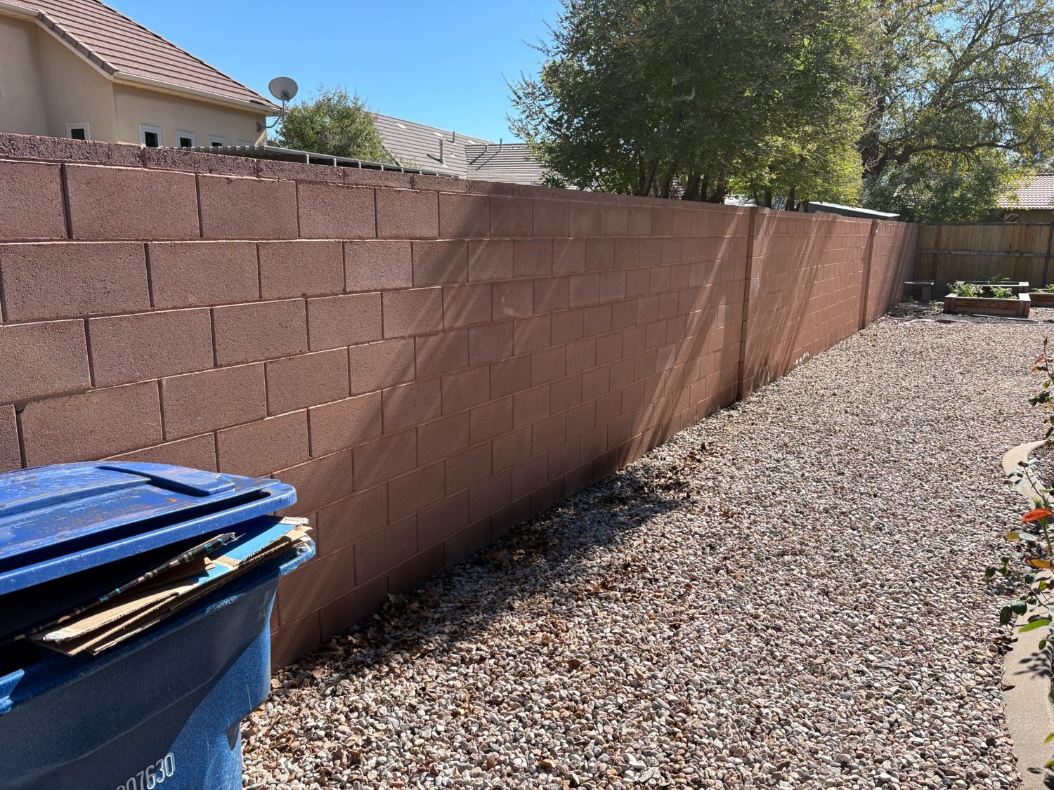 After junk removal: cleared gravel side yard alongside the block wall